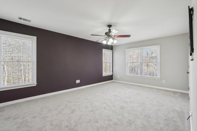 unfurnished room featuring light carpet, baseboards, visible vents, and a ceiling fan