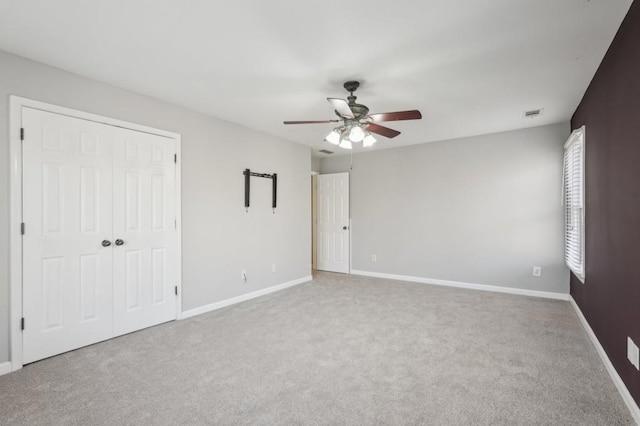 unfurnished bedroom with a closet, visible vents, a ceiling fan, carpet flooring, and baseboards