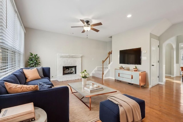 living area featuring arched walkways, a fireplace, recessed lighting, a ceiling fan, and wood finished floors