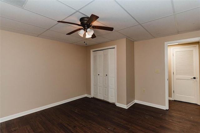 unfurnished bedroom with dark hardwood / wood-style flooring, a closet, a paneled ceiling, and ceiling fan