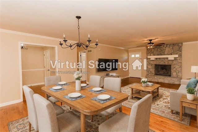 dining room with ornamental molding, ceiling fan with notable chandelier, a fireplace, and light hardwood / wood-style floors