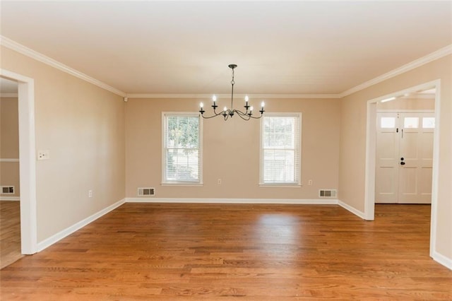 empty room with crown molding, wood-type flooring, and a chandelier