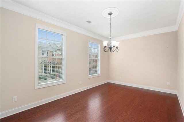 empty room featuring dark wood-type flooring, ornamental molding, and a chandelier