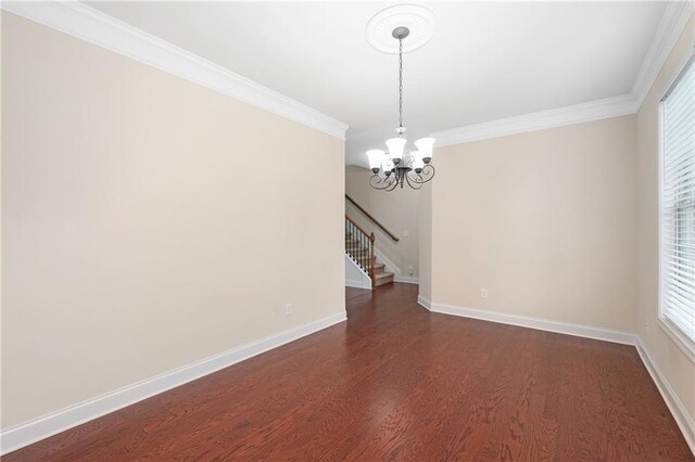 spare room featuring dark hardwood / wood-style flooring, ornamental molding, and a chandelier