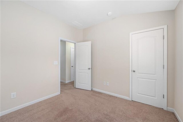 unfurnished bedroom with light colored carpet and vaulted ceiling