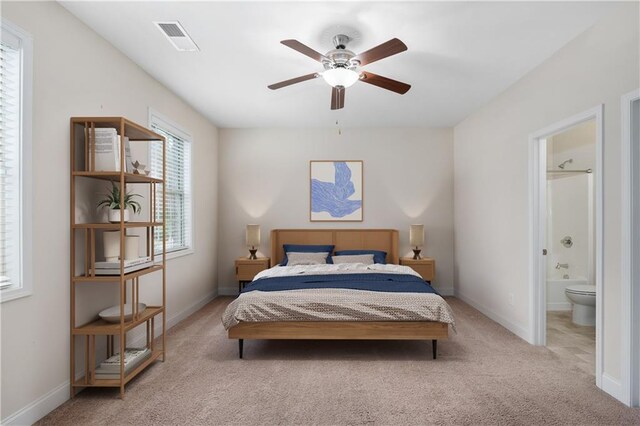 carpeted bedroom with ensuite bath and ceiling fan