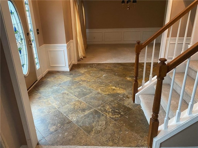 entrance foyer with wainscoting, a decorative wall, and stone tile floors