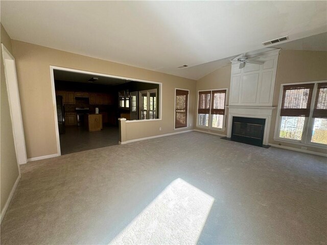 unfurnished living room featuring carpet, a large fireplace, visible vents, and vaulted ceiling