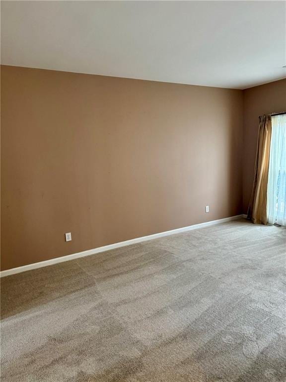 carpeted spare room featuring baseboards