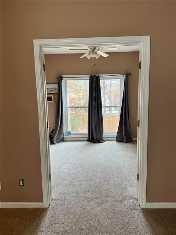 empty room featuring carpet floors, ceiling fan, and baseboards