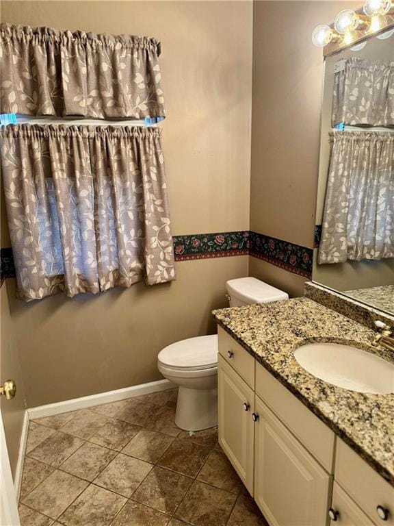 bathroom with toilet, baseboards, and vanity