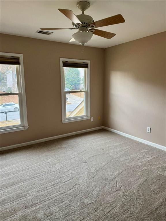 empty room with baseboards, visible vents, ceiling fan, and carpet flooring