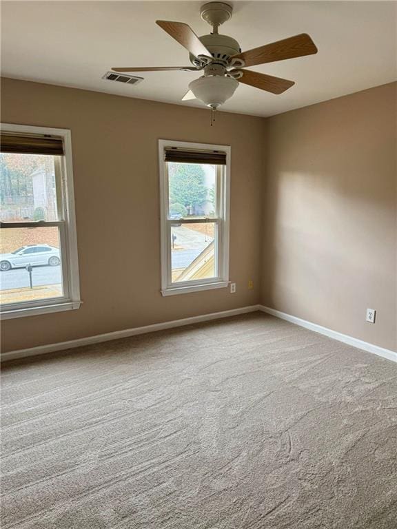 spare room featuring carpet floors, visible vents, ceiling fan, and baseboards