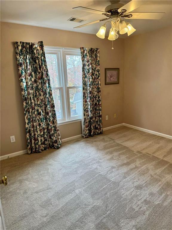 spare room featuring a ceiling fan, carpet flooring, visible vents, and baseboards