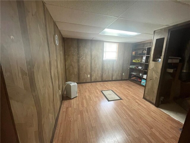 interior space with wooden walls, light hardwood / wood-style floors, and a drop ceiling