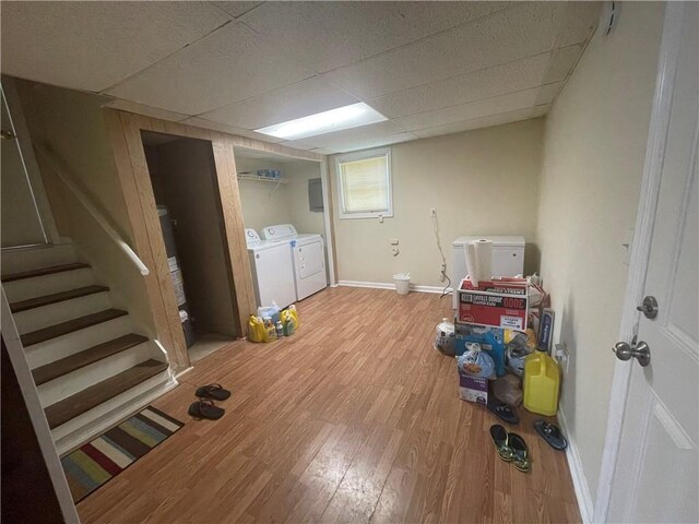 basement featuring separate washer and dryer, light hardwood / wood-style floors, and a drop ceiling