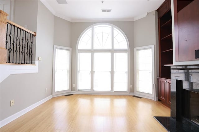 3541 Roswell Rd NE Unit 20, Atlanta, GA 30305 - unfurnished living room featuring a brick fireplace, light wood-type flooring, ornamental molding, and baseboards