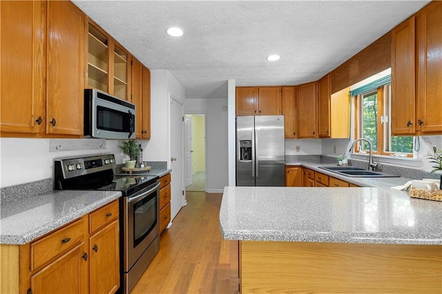 1920 Jett Ridge Rd, Cumming, GA 30041 - kitchen with stainless steel appliances, a sink, a peninsula, light wood finished floors, and brown cabinets
