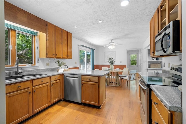 1920 Jett Ridge Rd, Cumming, GA 30041 - kitchen with stainless steel appliances, a sink, a peninsula, brown cabinetry, and light wood-style flooring