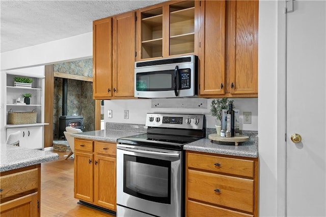 1920 Jett Ridge Rd, Cumming, GA 30041 - kitchen with appliances with stainless steel finishes, a wood stove, a textured ceiling, light wood finished floors, and light countertops