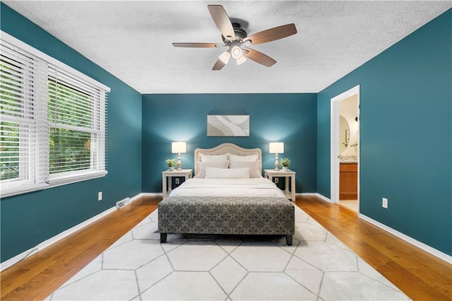 1920 Jett Ridge Rd, Cumming, GA 30041 - bedroom featuring wood finished floors, connected bathroom, ceiling fan, a textured ceiling, and baseboards