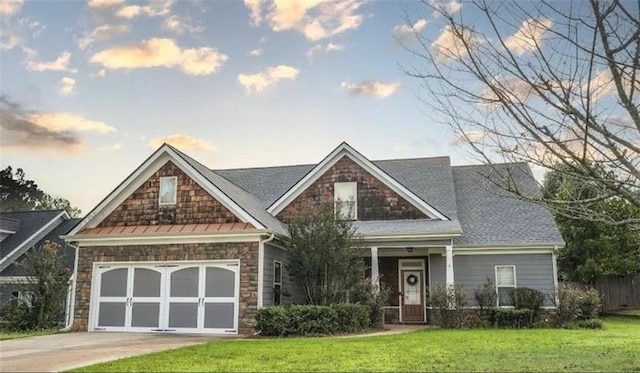 craftsman inspired home featuring a front lawn, an attached garage, stone siding, and driveway