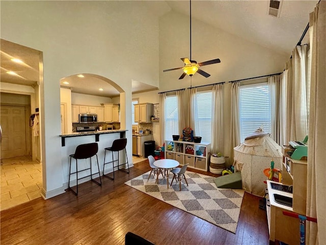 living room featuring a wealth of natural light, arched walkways, ceiling fan, and wood-type flooring