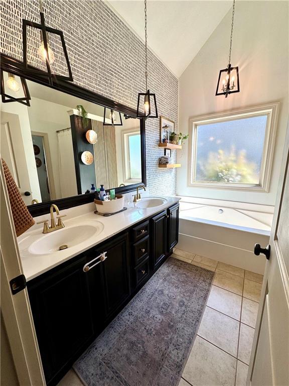 full bath featuring an inviting chandelier, double vanity, tile patterned floors, and a sink