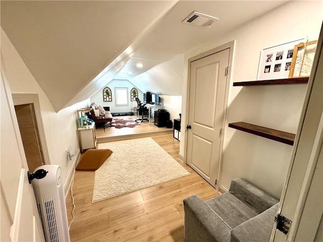 interior space featuring vaulted ceiling, radiator, visible vents, and light wood-type flooring