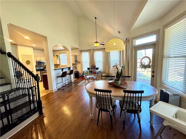 dining room with ceiling fan, stairway, a wealth of natural light, and wood finished floors