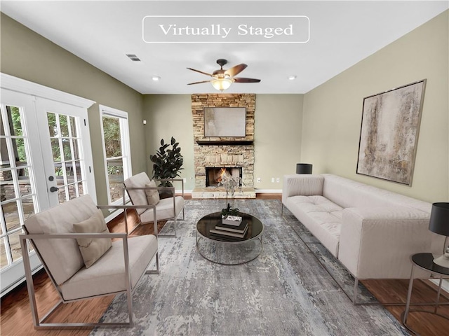 living room featuring french doors, ceiling fan, a fireplace, and hardwood / wood-style floors