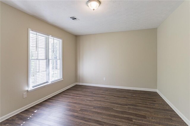 unfurnished room with dark hardwood / wood-style floors and a textured ceiling