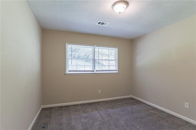 carpeted empty room featuring a textured ceiling