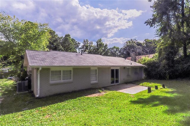 rear view of property with central air condition unit, a patio, and a yard