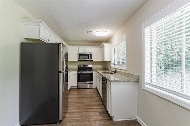 kitchen featuring sink, white cabinetry, stainless steel appliances, light stone countertops, and dark hardwood / wood-style flooring