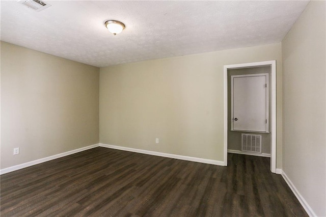 spare room featuring dark wood-type flooring and a textured ceiling