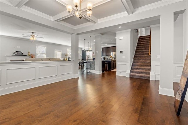 unfurnished living room with coffered ceiling, ceiling fan with notable chandelier, ornamental molding, beamed ceiling, and dark hardwood / wood-style flooring