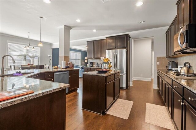 kitchen featuring sink, a center island, dark hardwood / wood-style floors, pendant lighting, and appliances with stainless steel finishes