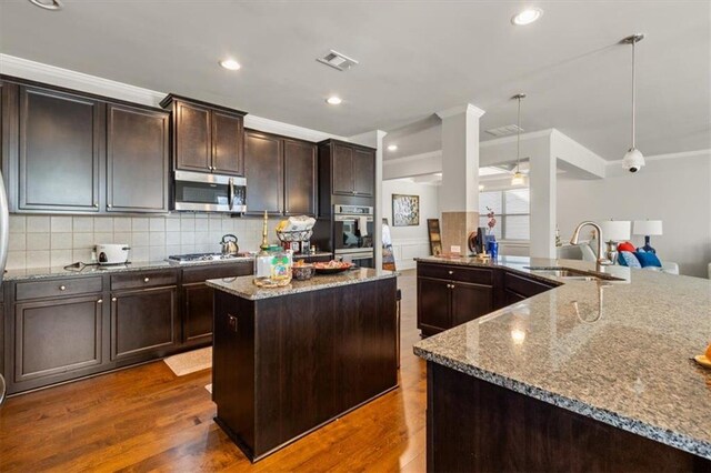 kitchen with sink, stainless steel appliances, dark hardwood / wood-style flooring, decorative light fixtures, and a kitchen island