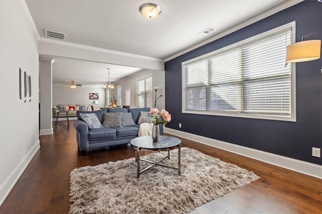 living room featuring wood-type flooring, ceiling fan with notable chandelier, and ornamental molding