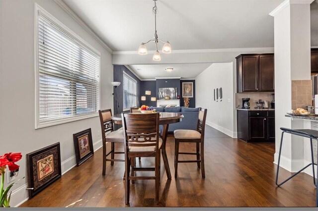 dining area with dark wood-type flooring, a notable chandelier, and ornamental molding