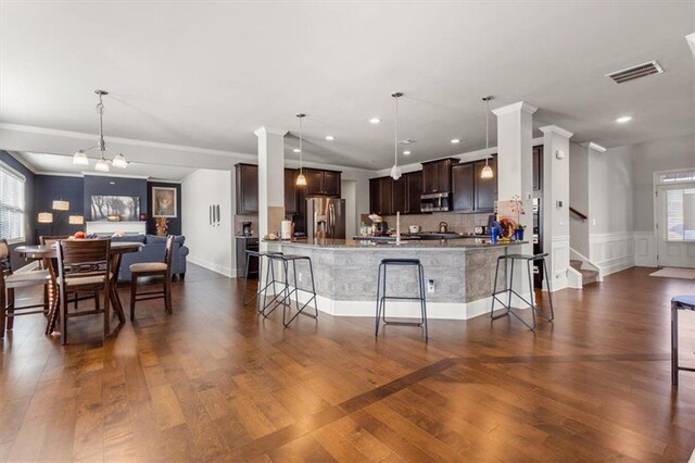 kitchen with a kitchen breakfast bar, pendant lighting, a healthy amount of sunlight, and appliances with stainless steel finishes