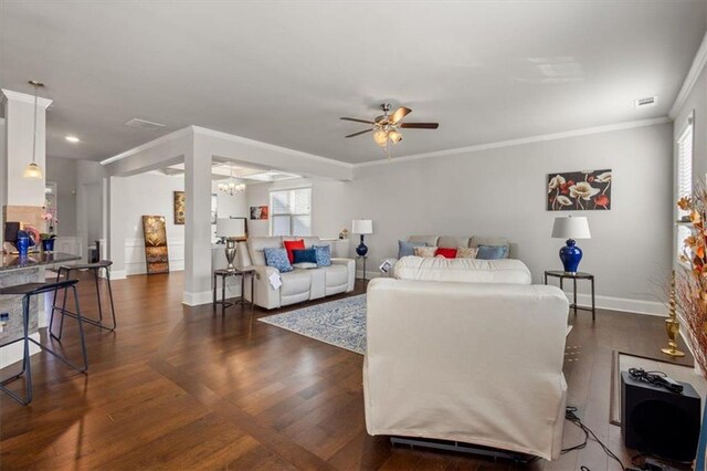 living room with a wealth of natural light, crown molding, ceiling fan with notable chandelier, and dark hardwood / wood-style floors