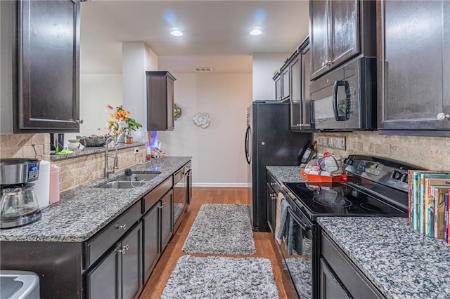 kitchen with decorative backsplash, light wood-type flooring, sink, and black appliances