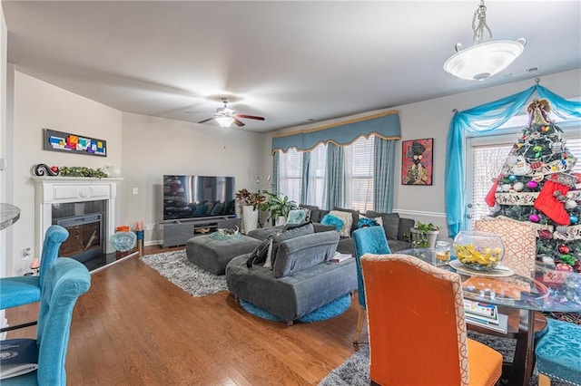 living room with a tiled fireplace, ceiling fan, and hardwood / wood-style floors