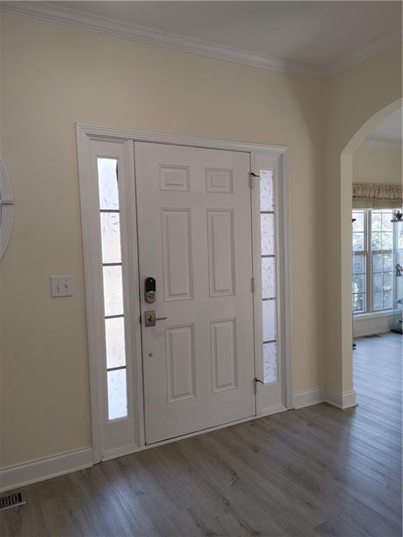 entryway featuring baseboards, visible vents, arched walkways, ornamental molding, and wood finished floors