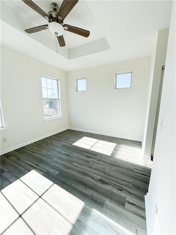 empty room featuring dark wood-type flooring, ceiling fan, and a raised ceiling