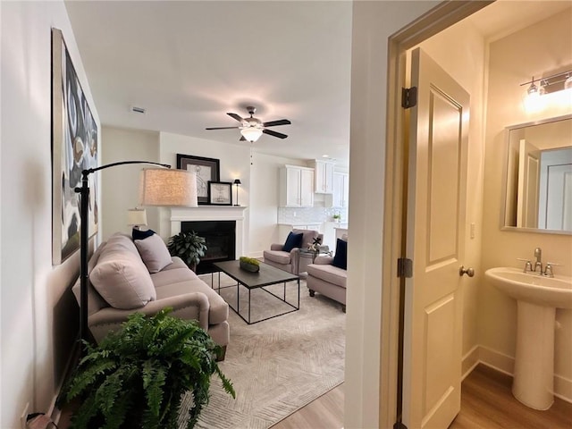 living room featuring light hardwood / wood-style floors, ceiling fan, and sink