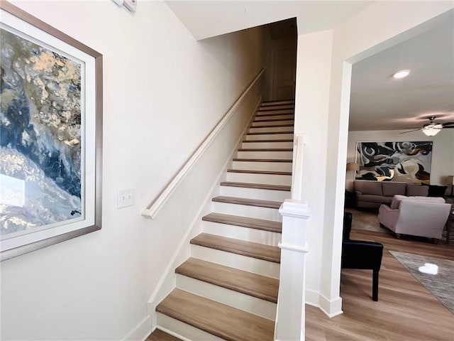 stairway with ceiling fan and hardwood / wood-style flooring