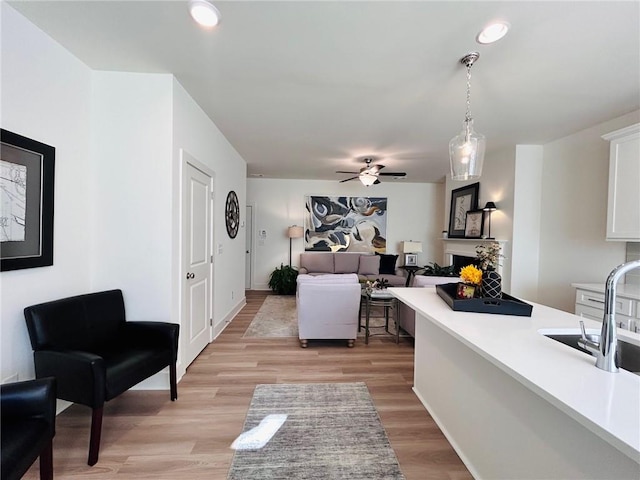 living room featuring light wood-type flooring, ceiling fan, and sink